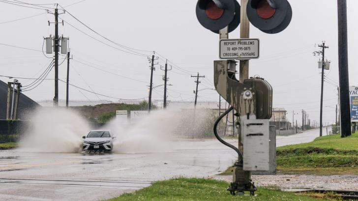 A car splashes water on a partially flooded roadway in Galveston 