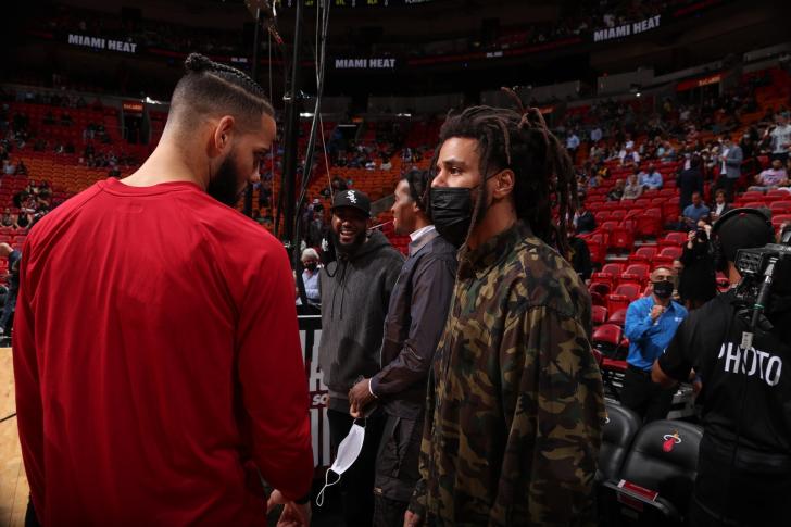 Rapper J. Cole talks with Caleb Martin of the Miami Heat before the game against the New York Knicks on January 26 2021...