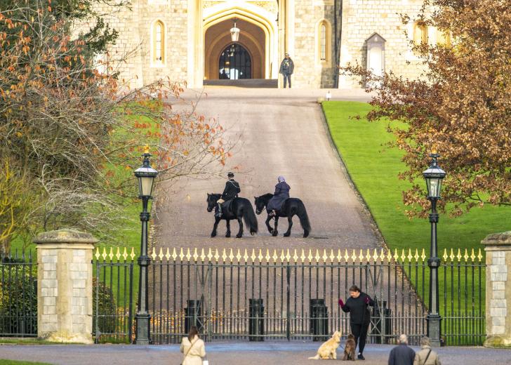  The Queen riding her horse accompanied by Head Groom Terry Pendry in the grounds of Windsor Castle