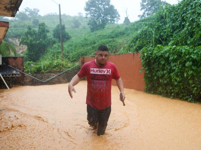 A man walks on a road flooded by Hurricane Fiona in Cayey, Puerto Rico on Sunday.